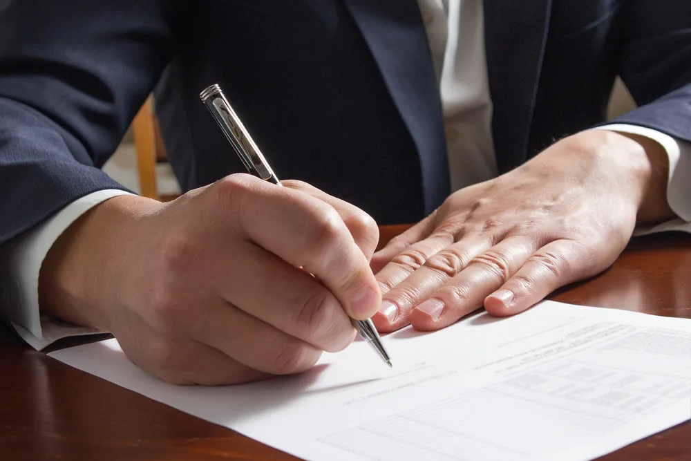 Photo of a man writing an paper at the table